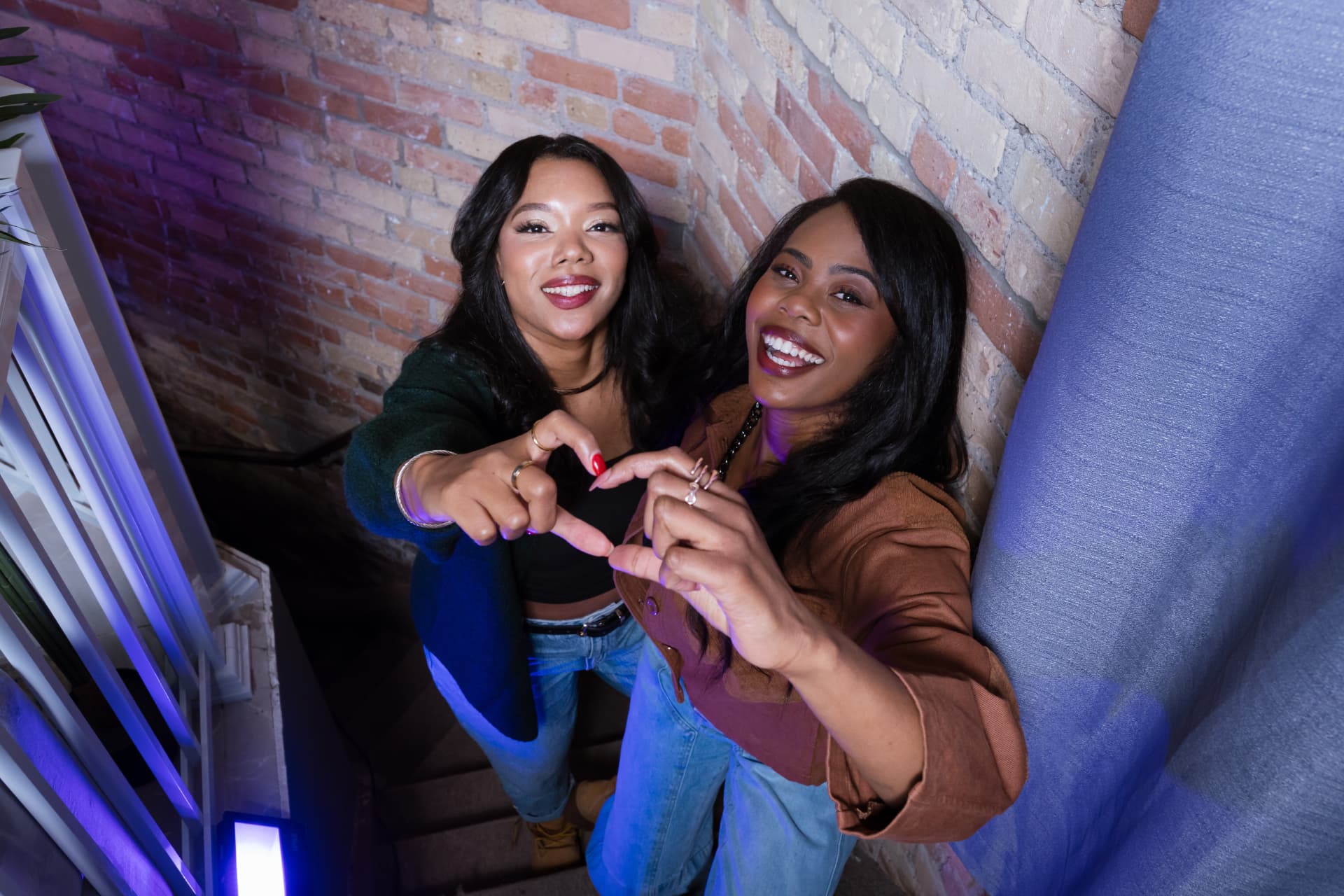 Jayne and Shawna making a heart with their hands in the stairwell